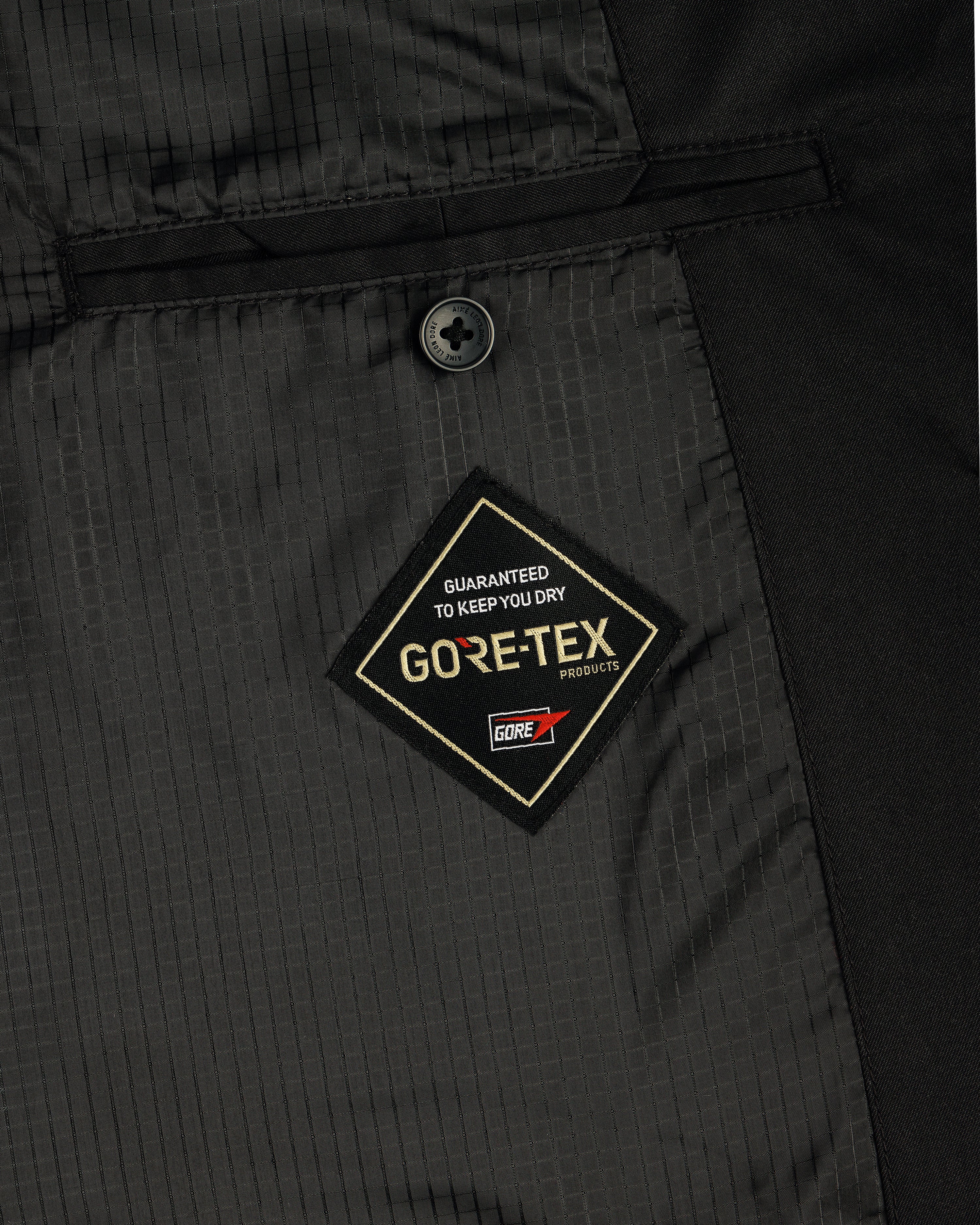 Close-up of the GORE-TEX Balmacaan Coat’s inside pocket featuring a GORE-TEX label and a single black button above it.
