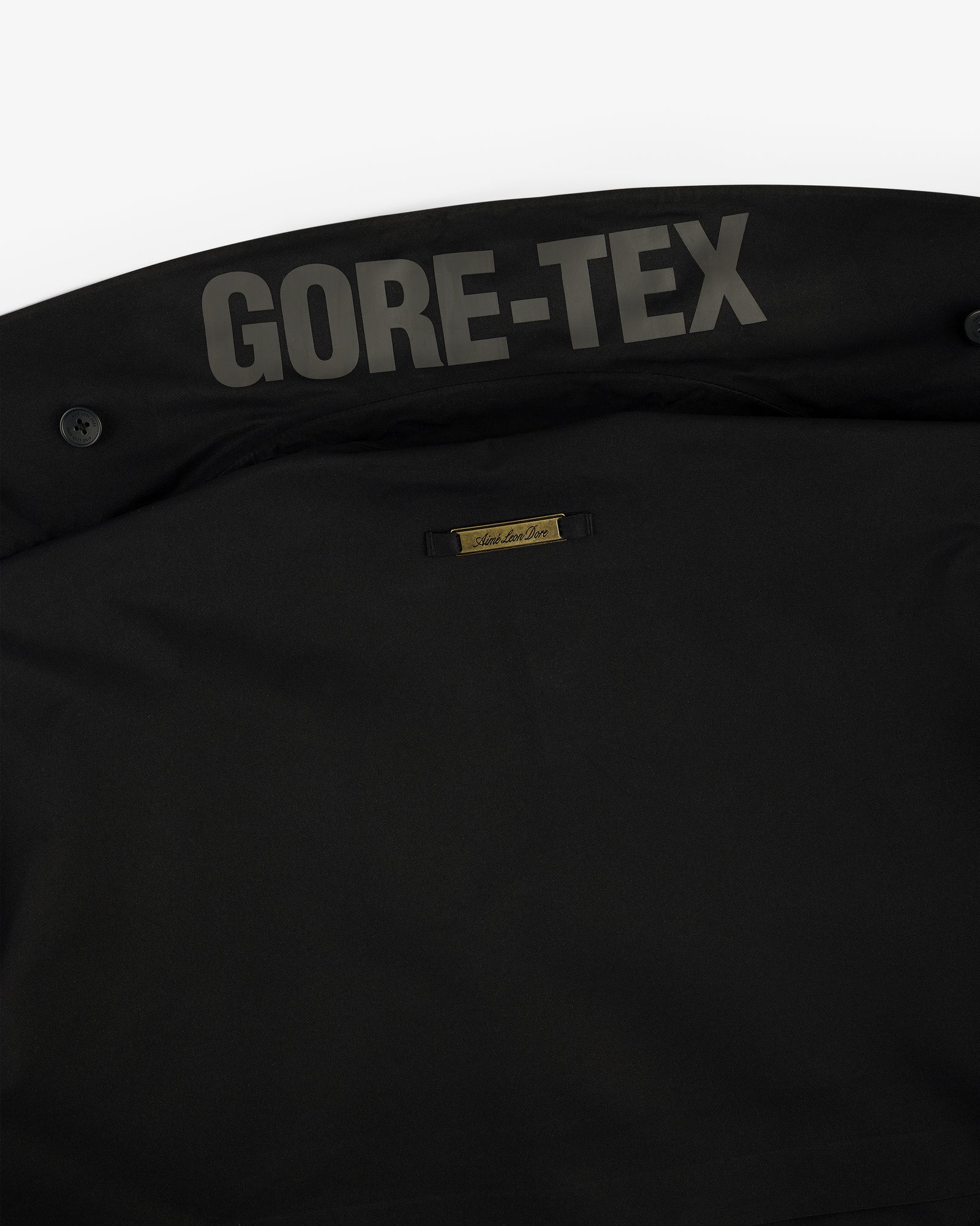 Close-up of the GORE-TEX Balmacaan Coat’s black inner collar with the GORE-TEX logo and small gold label.
