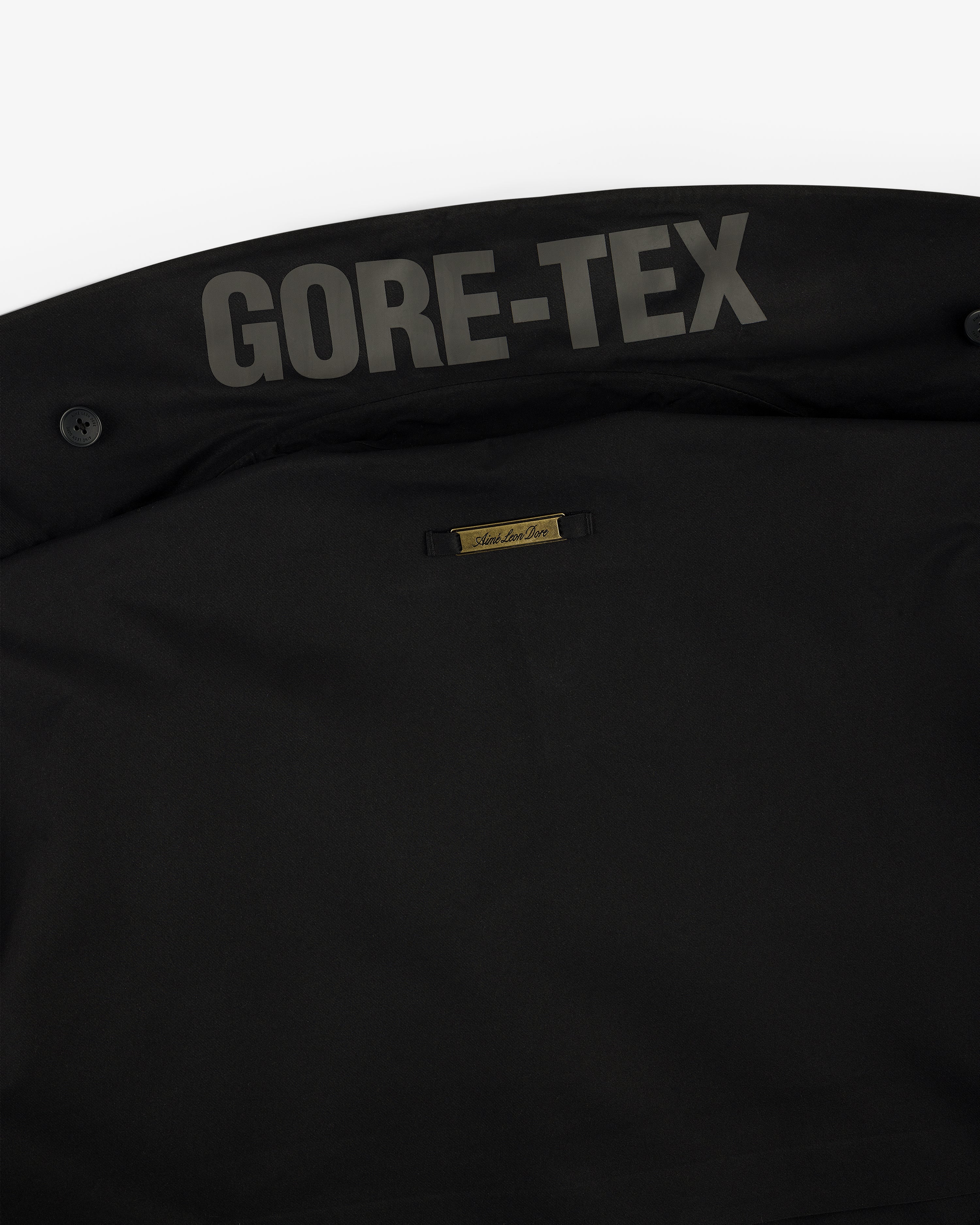 Close-up of the GORE-TEX Balmacaan Coat’s black inner collar with the GORE-TEX logo and small gold label.