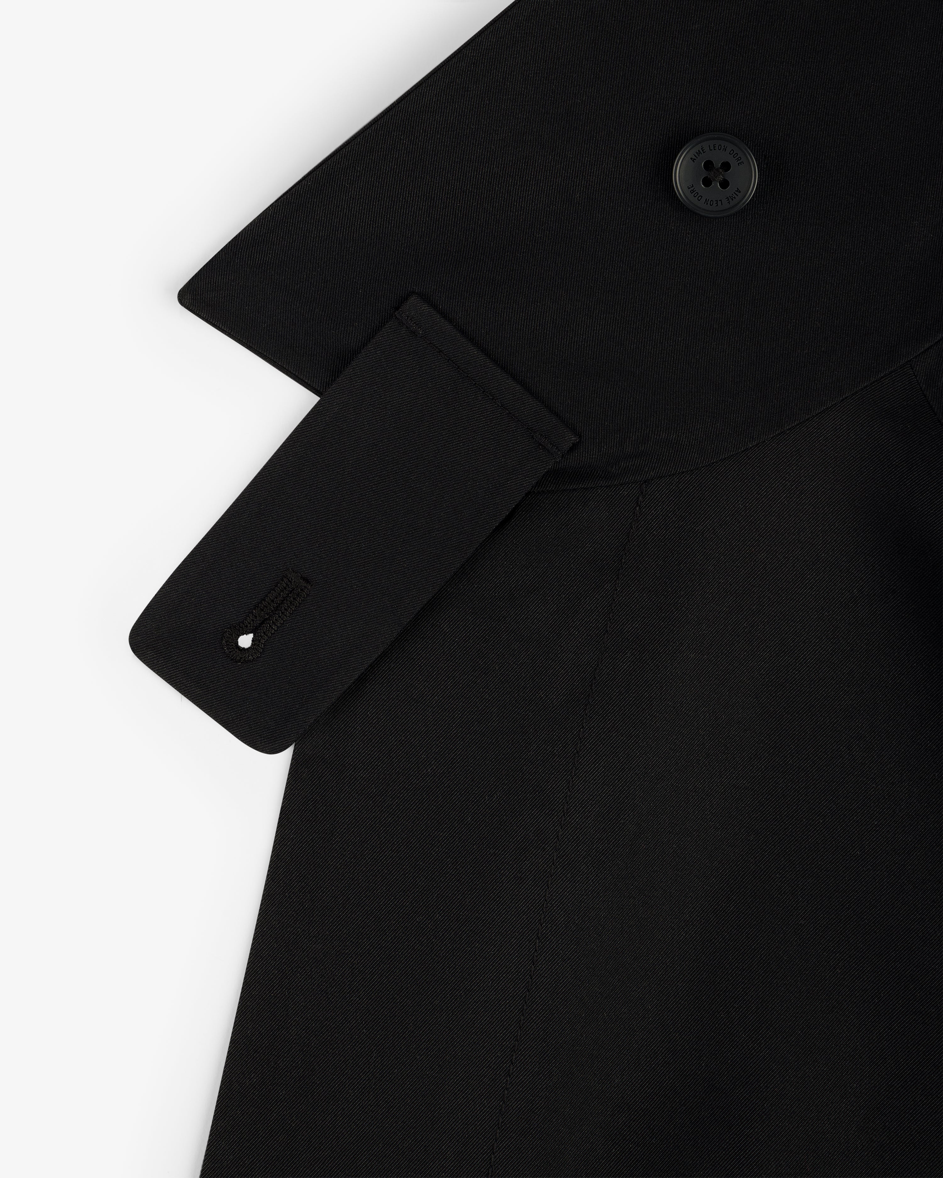 Close-up of GORE-TEX Balmacaan Coat shoulder with button, collar detail, and strap featuring a stitched buttonhole.