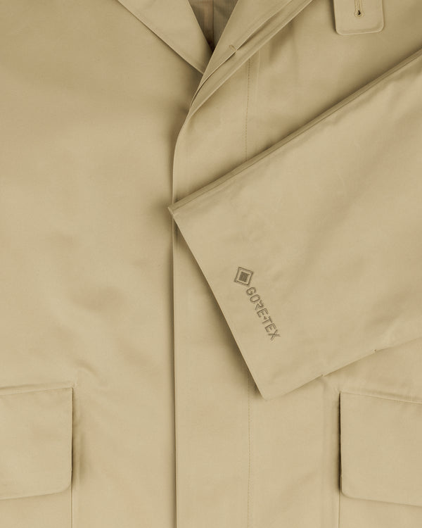 Close-up of the beige GORE-TEX Balmacaan Coat with two front pockets and a GORE-TEX logo on the sleeve.