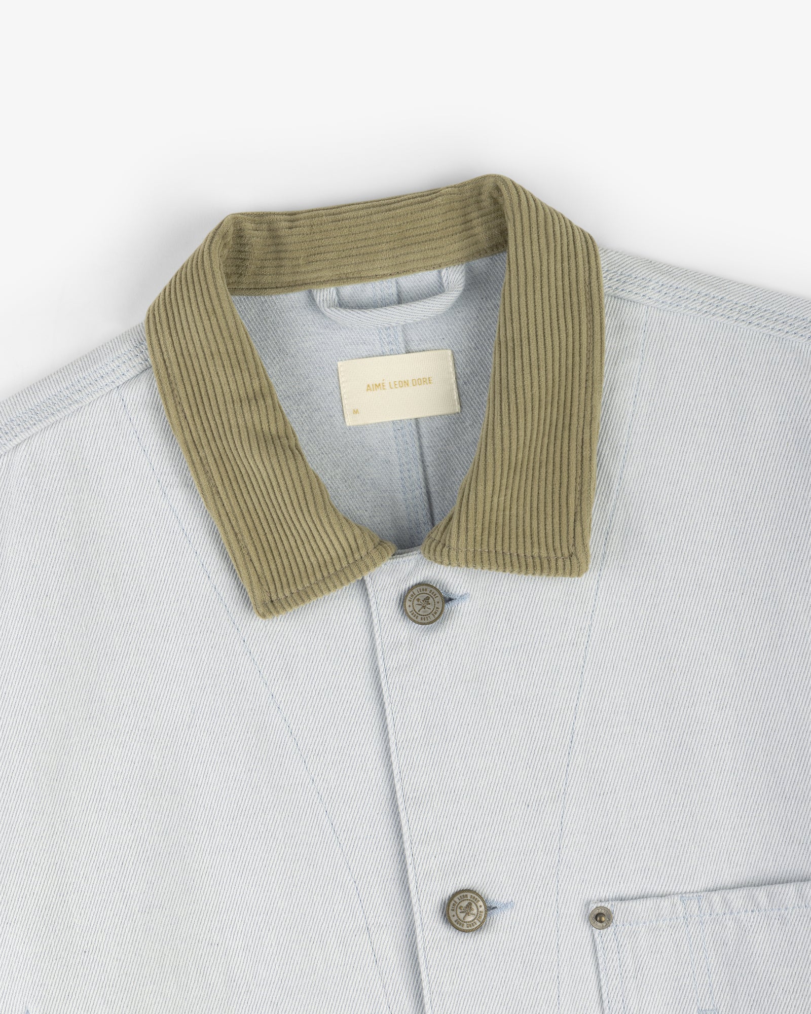 Denim Barn Jacket in light blue with ribbed olive green collar, visible buttons, and a chest pocket.