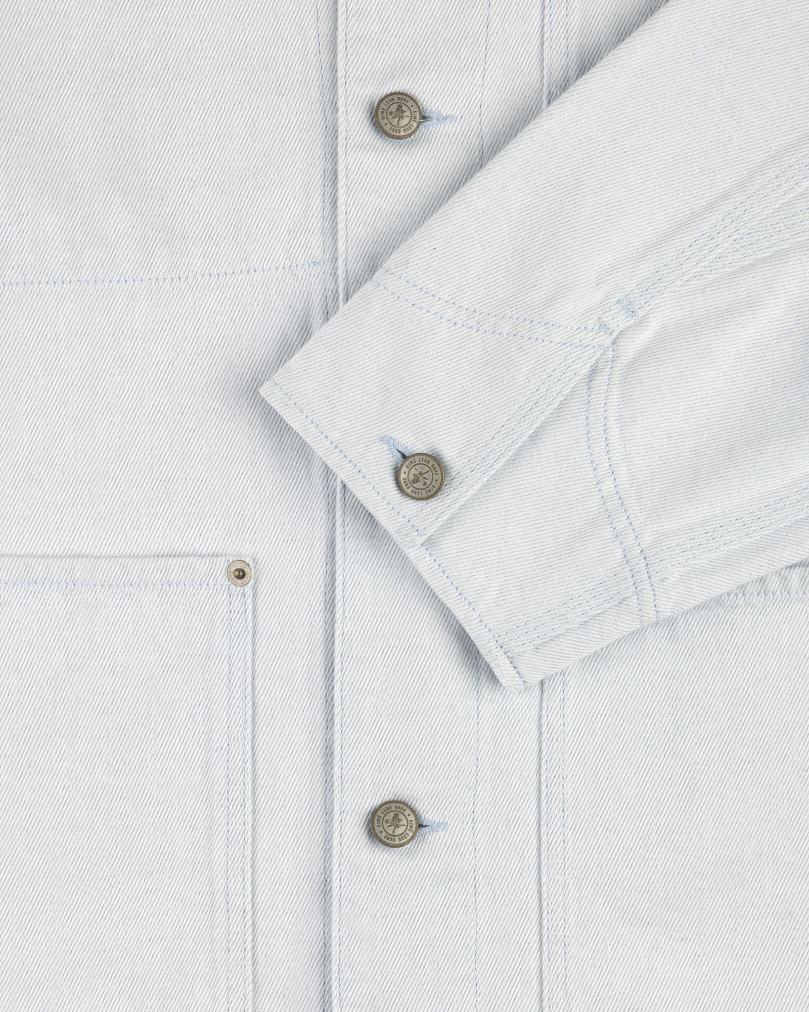 Close-up of a Denim Barn Jacket with metal buttons, visible stitching, chest pocket, and sleeve cuff.