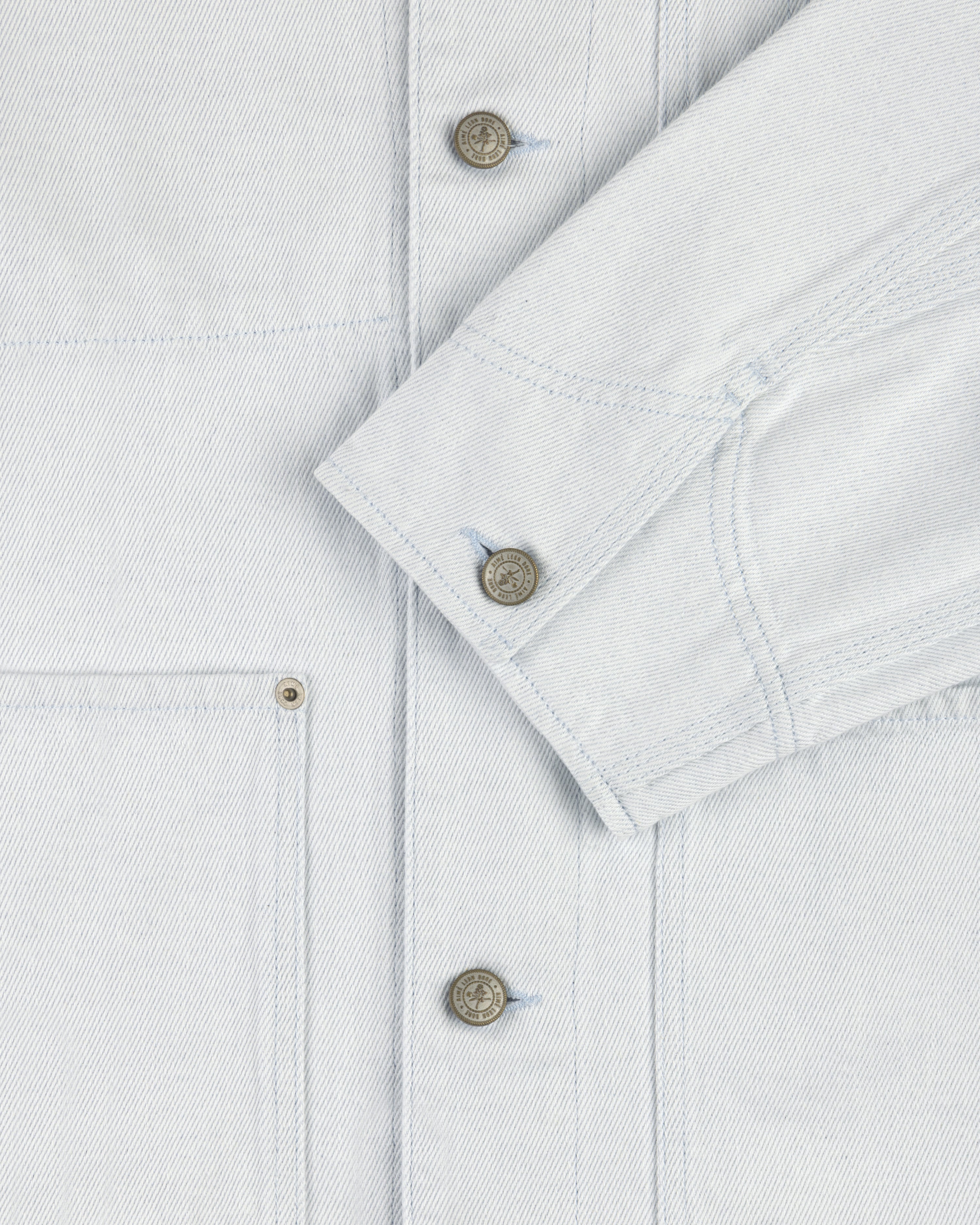Close-up of a Denim Barn Jacket with metal buttons, visible stitching, chest pocket, and sleeve cuff.
