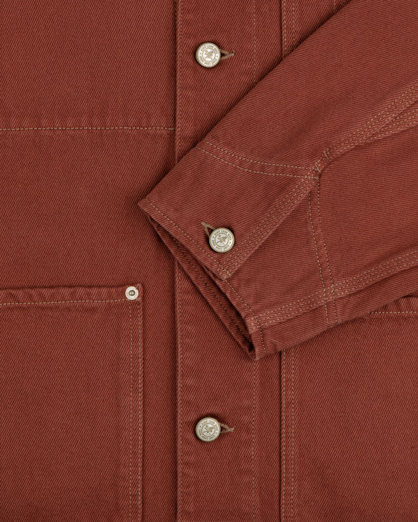 Close-up of the Denim Barn Jacket in rust, highlighting metal buttons, stitching, pocket, and sleeve.
