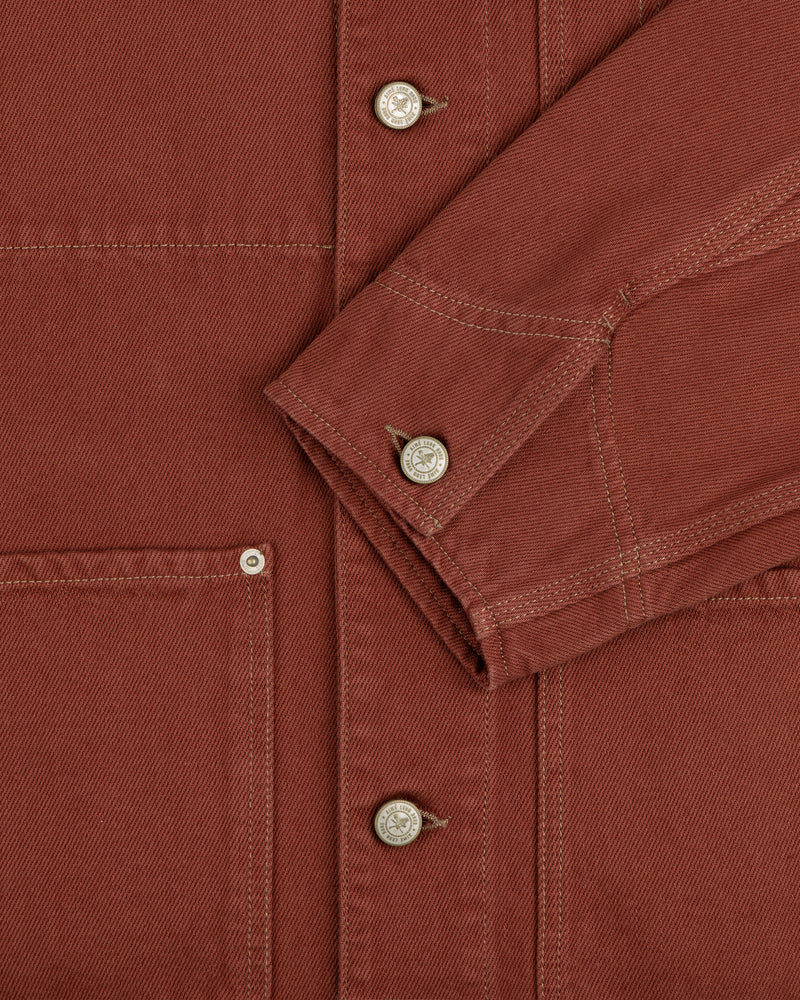 Close-up of the Denim Barn Jacket in rust, highlighting metal buttons, stitching, pocket, and sleeve.