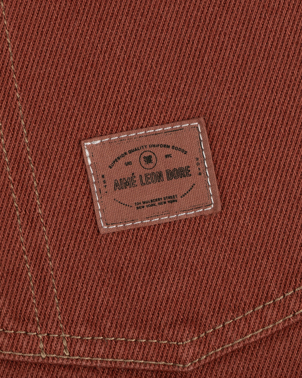 Close-up of the Denim Barn Jacket's brown fabric with a stitched AIMÉ LEON DORE label and white contrast stitching.