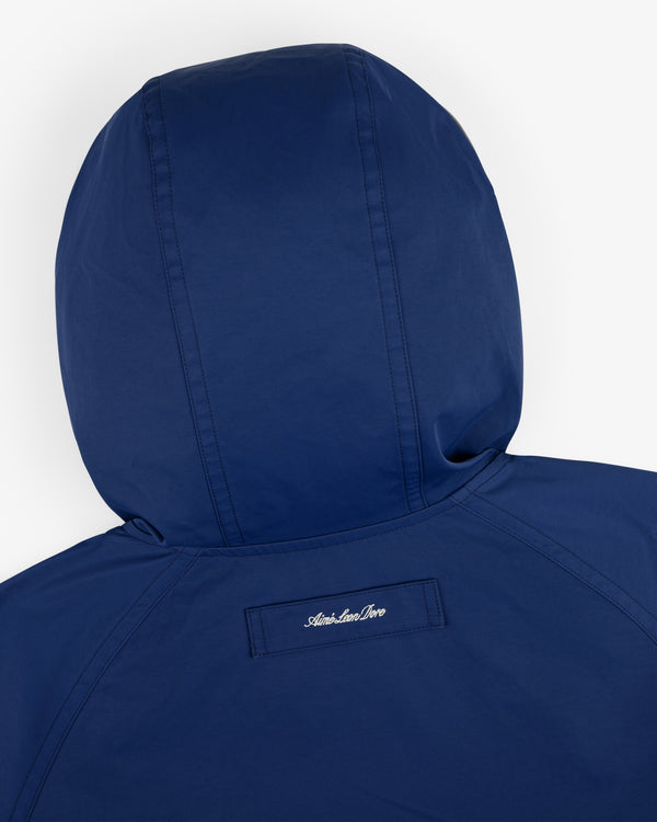 A blue Reversible Madras Windbreaker with "American River" embroidered in white on the upper back.