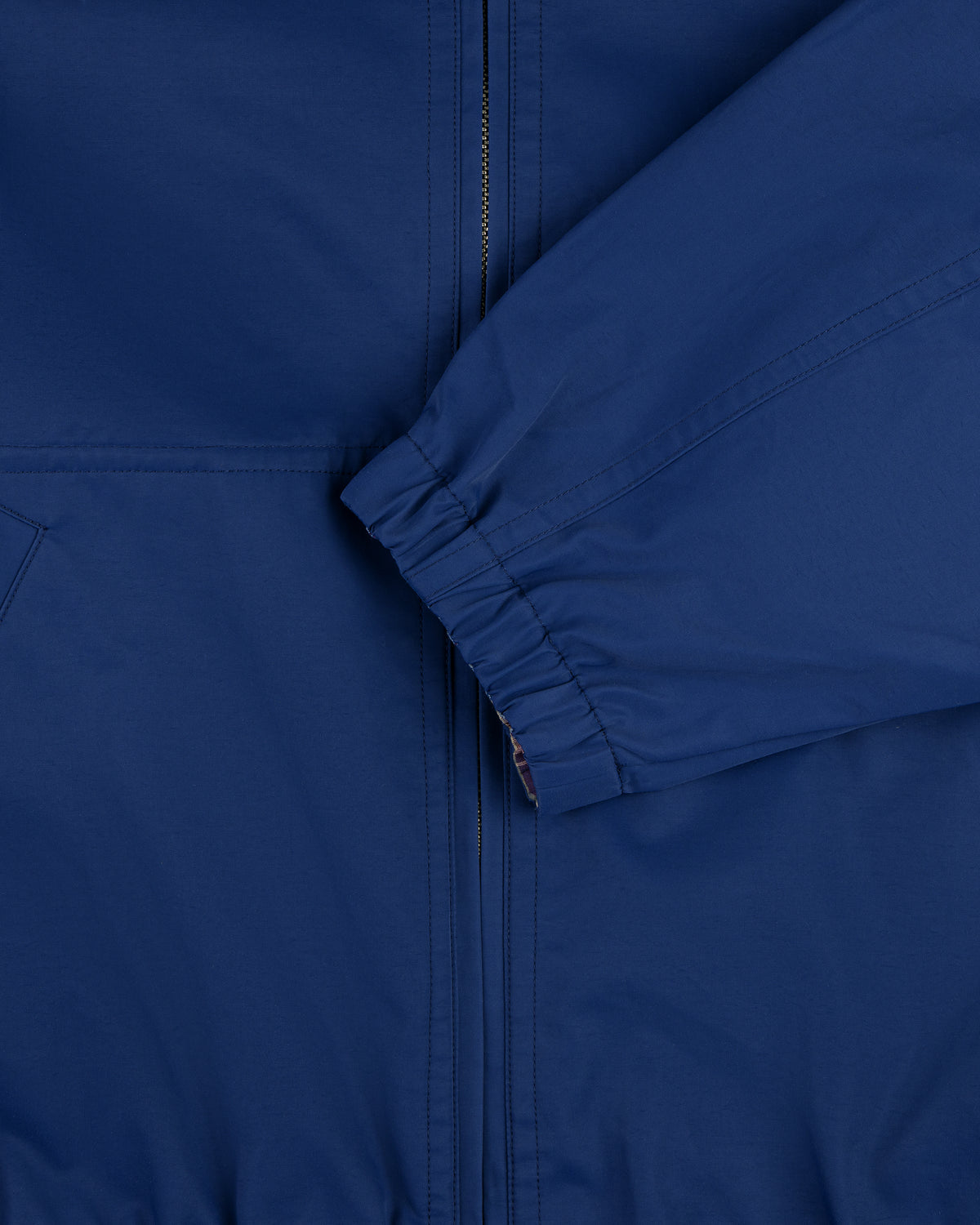 Close-up of the Reversible Madras Windbreaker, featuring a blue zipper and elastic cuff sleeve in front.