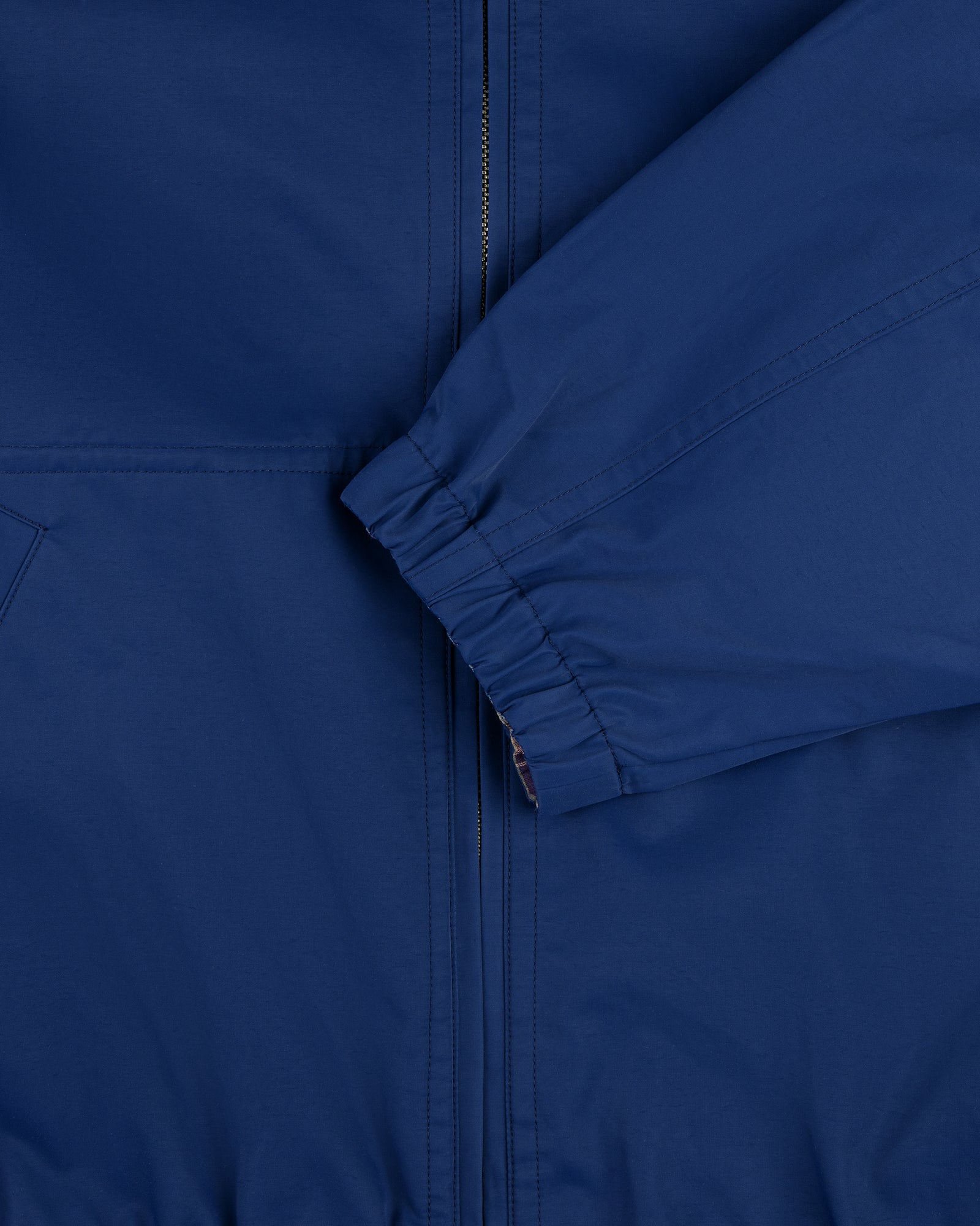 Close-up of the Reversible Madras Windbreaker, featuring a blue zipper and elastic cuff sleeve in front.