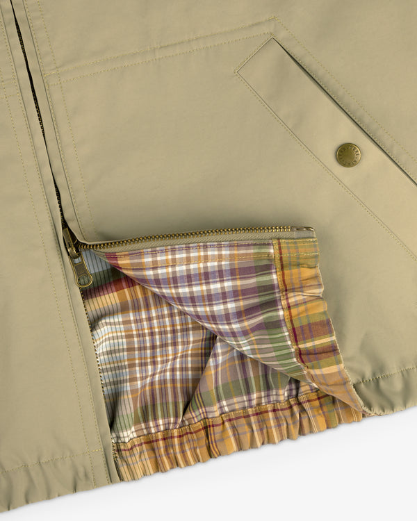 Close-up of the Reversible Madras Windbreaker, beige with a zippered front and a vibrant plaid lining inside.