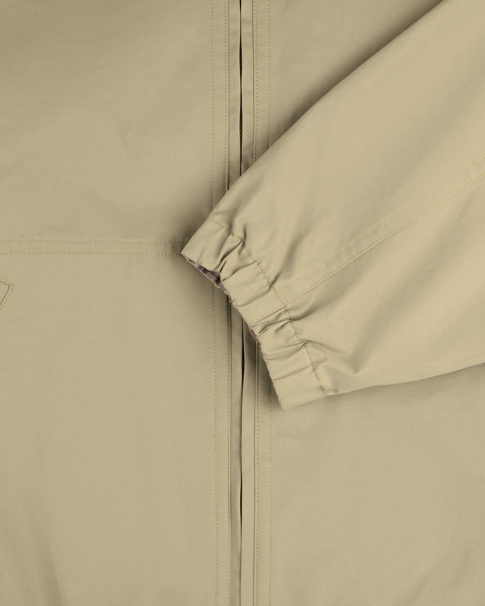 Close-up of the Reversible Madras Windbreaker in beige, highlighting the elastic cuffed sleeve and partial zipper.