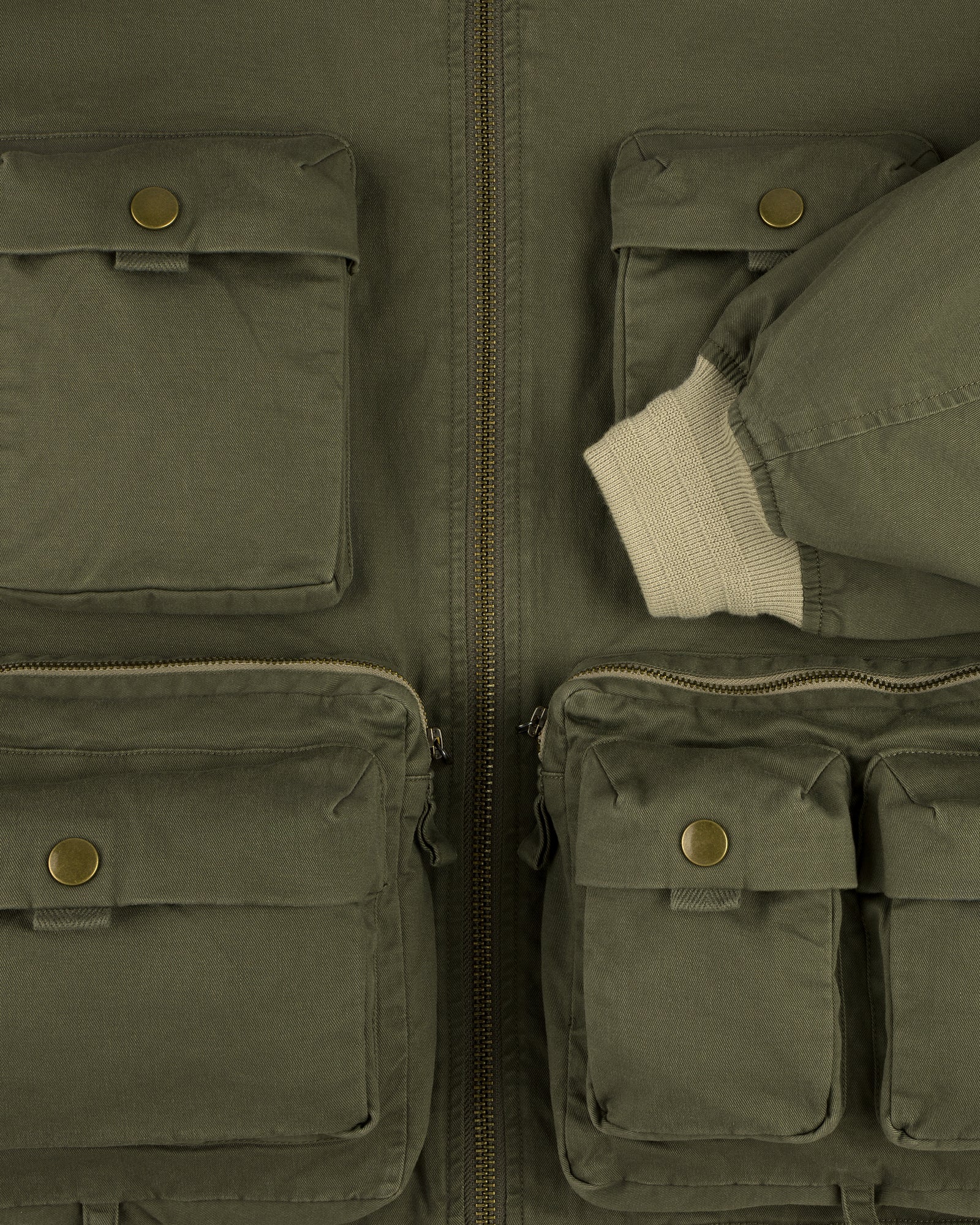 Close-up of the Safari Utility Bomber in olive green with multiple front pockets and a cream ribbed cuff.