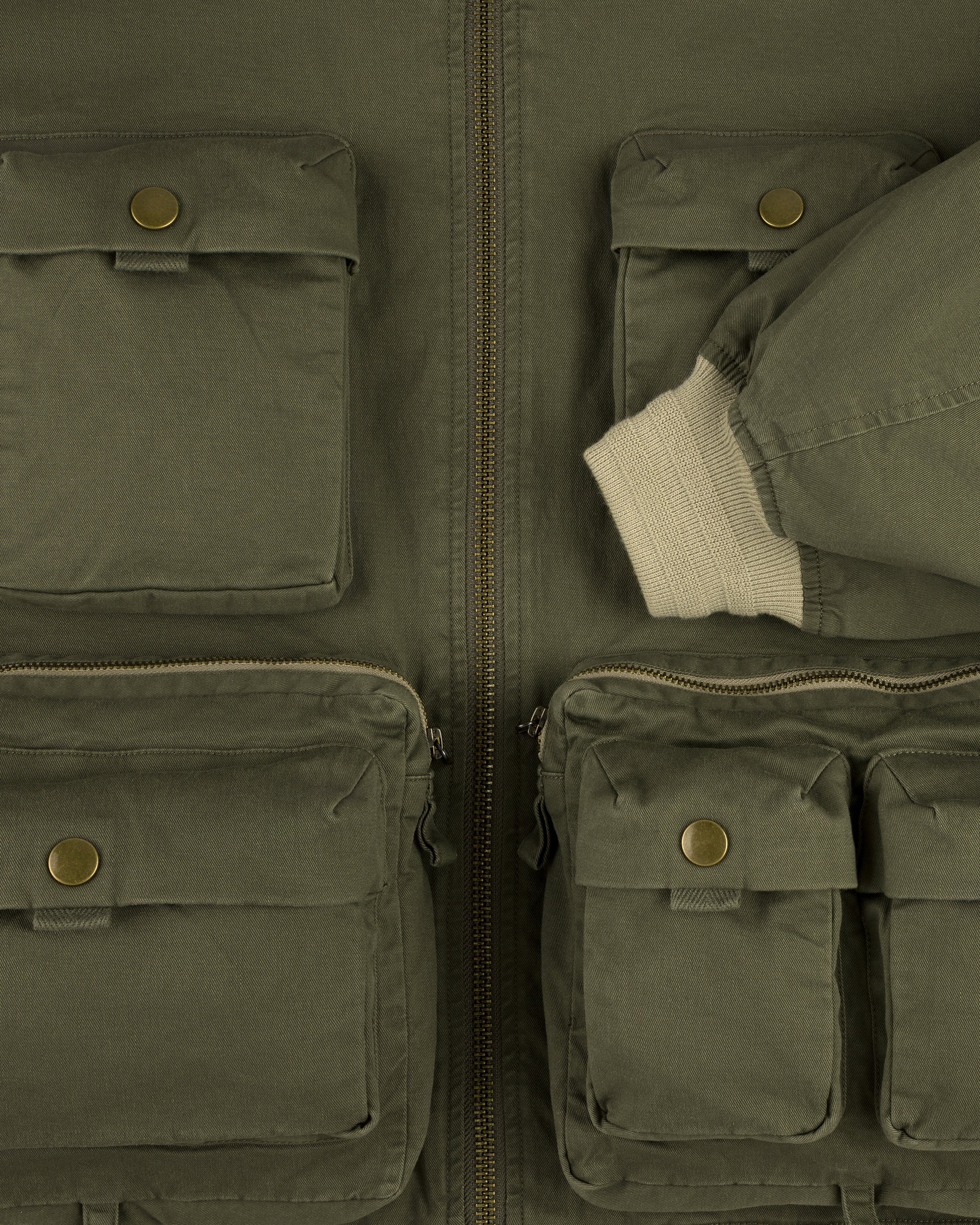 Close-up of the Safari Utility Bomber in olive green with multiple front pockets and a cream ribbed cuff.