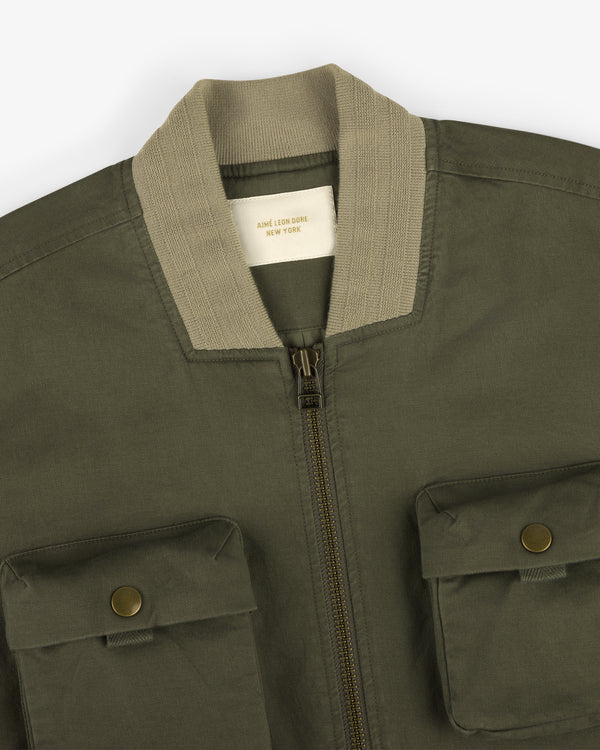 Safari Utility Bomber: olive green with beige ribbed collar, zip front, and two button-flap chest pockets.