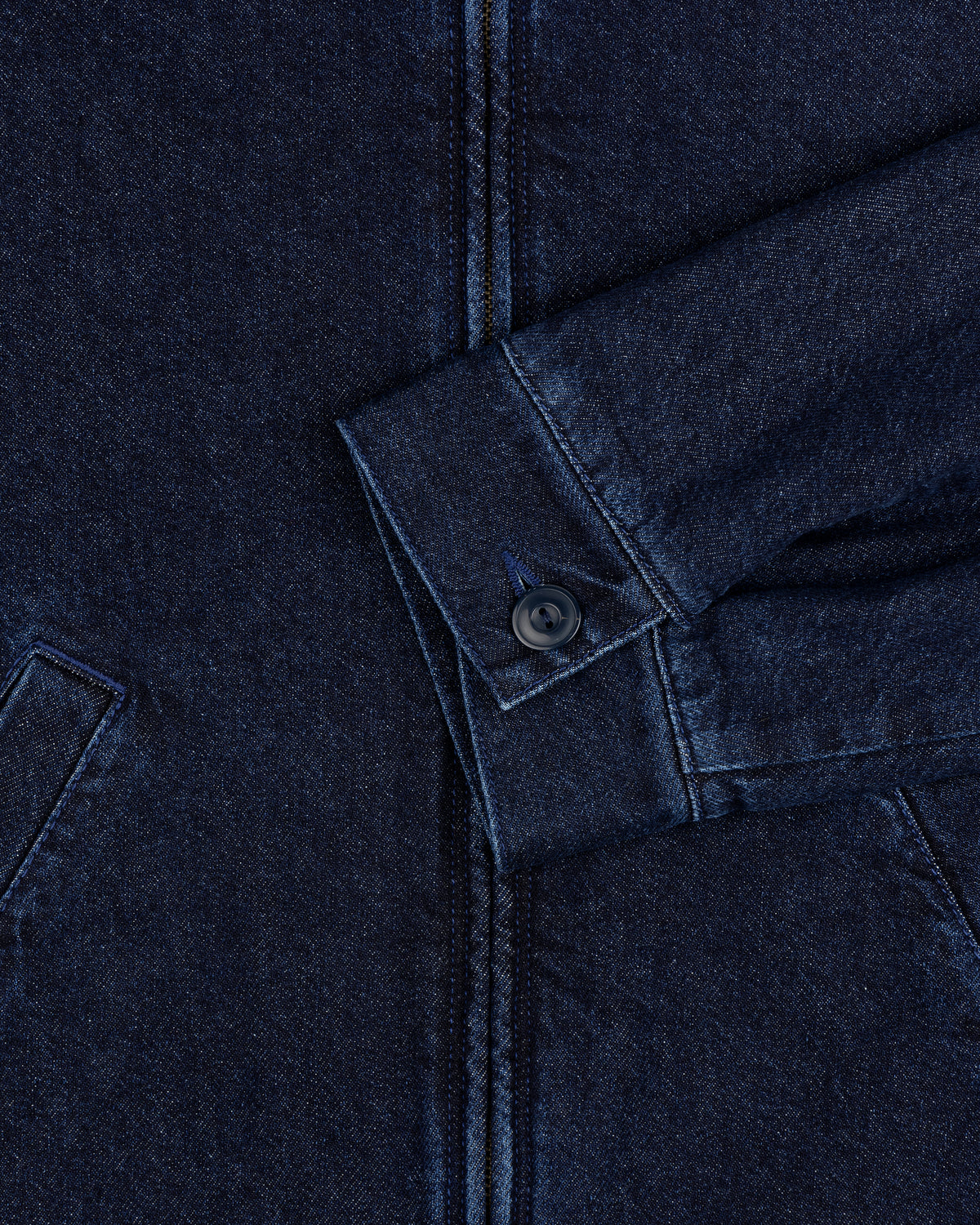 Close-up of a Denim Zip Jacket sleeve in dark blue with a buttoned cuff and visible pocket seams.