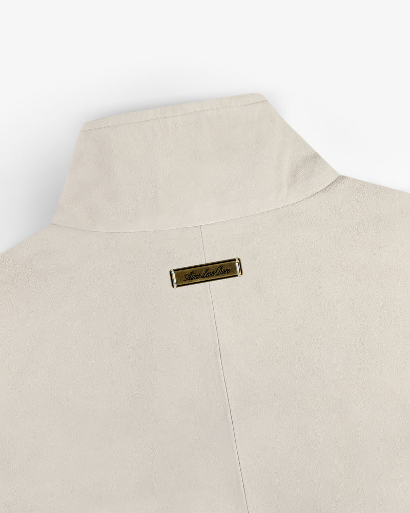 Suede Track Jacket in beige with a tall collar and small gold nameplate on the back near the neckline.