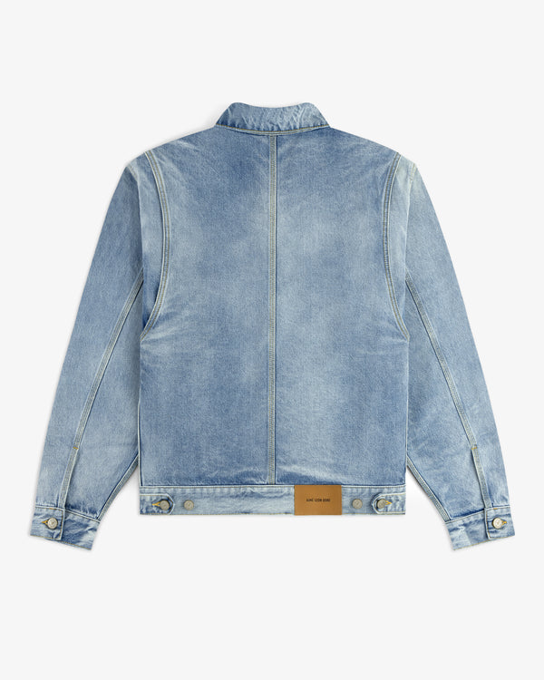 The Denim Trucker Jacket is light blue with a tan leather patch near the bottom hem on the back.