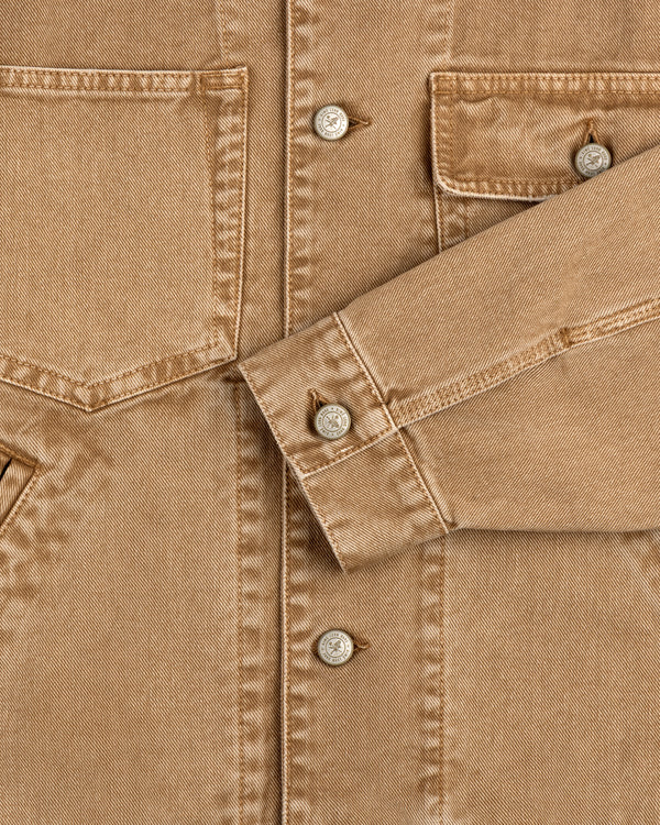 Close-up of a Denim Trucker Jacket highlighting tan fabric, buttons, breast pockets, and detailed stitching.