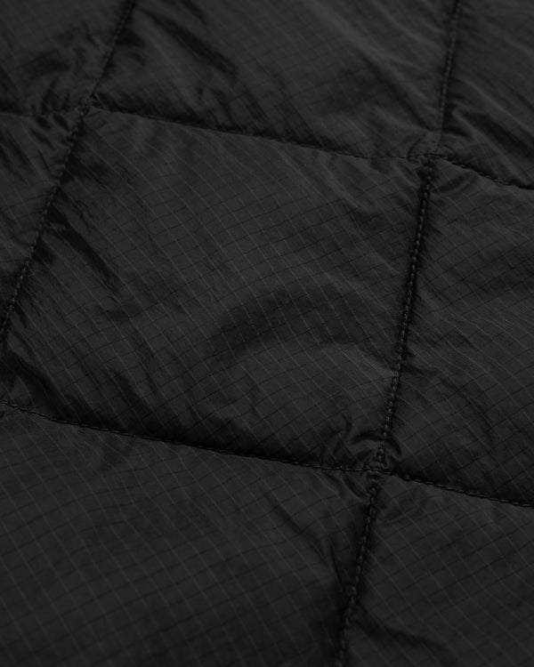 Close-up of black quilted fabric on the Nylon Quilted Unisphere Jacket, highlighting grid pattern and stitching.