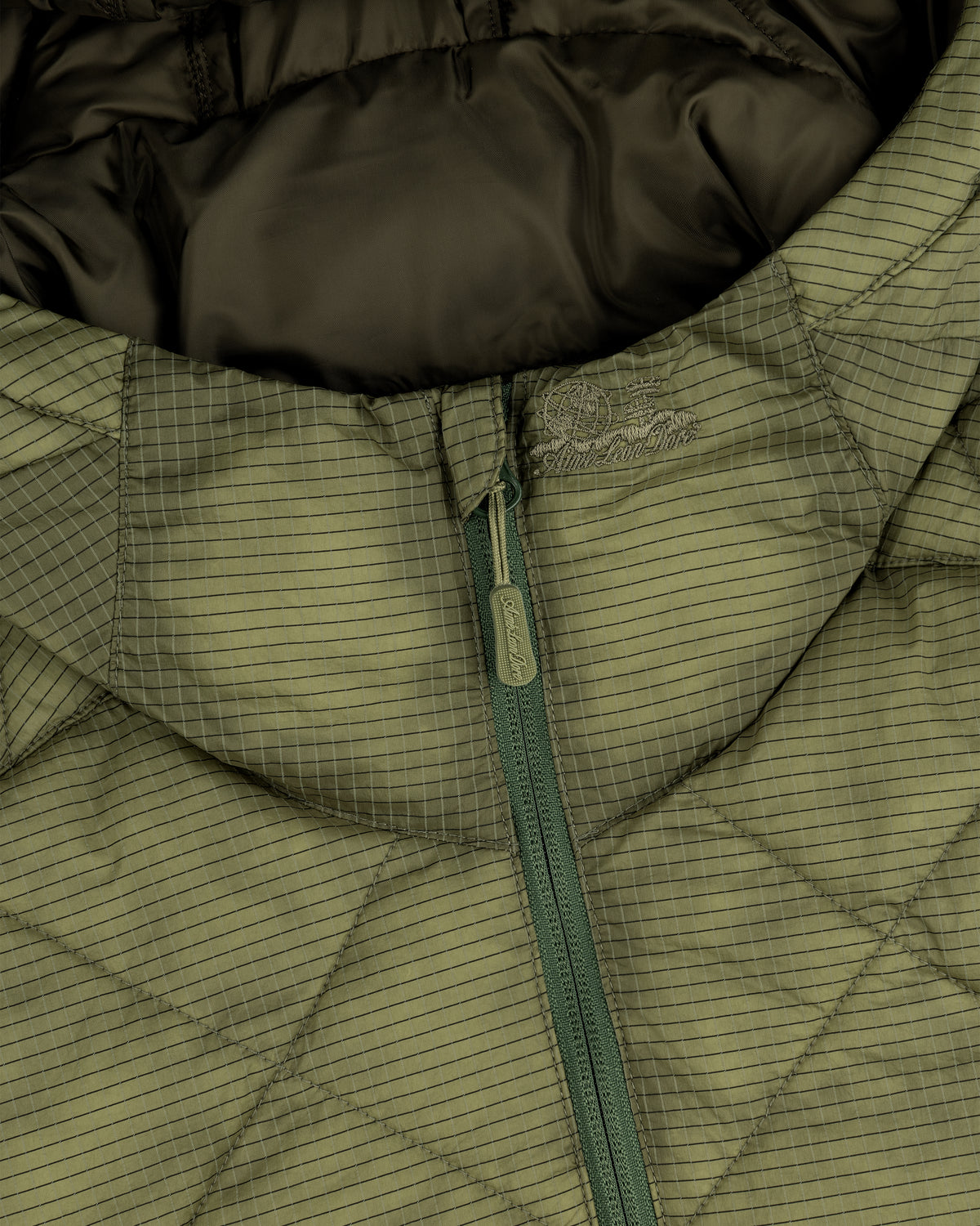Close-up of the Nylon Quilted Unisphere Jacket in olive green, featuring a zip front and grid pattern.