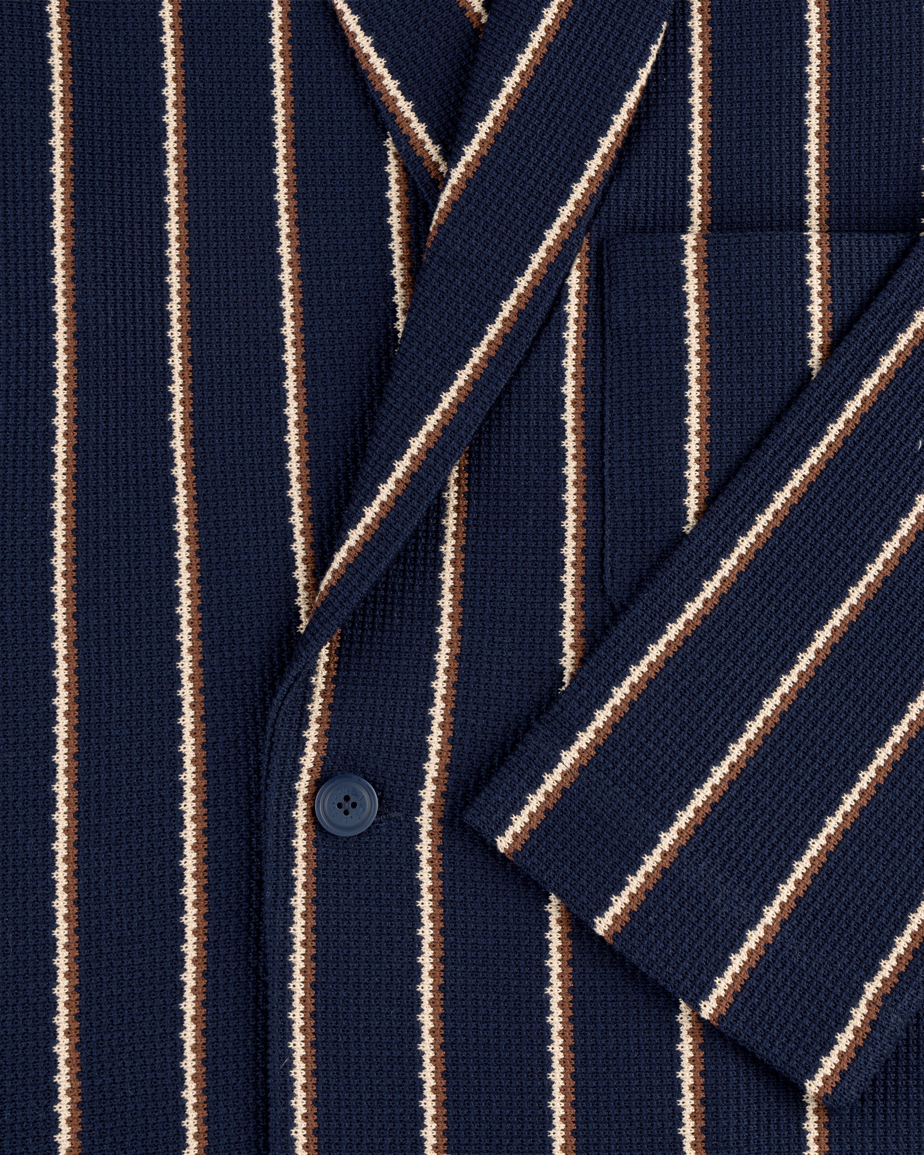 Close-up of the Striped Jacquard Shawl Collar Jacket in navy with white and brown stripes, front pocket, and button.