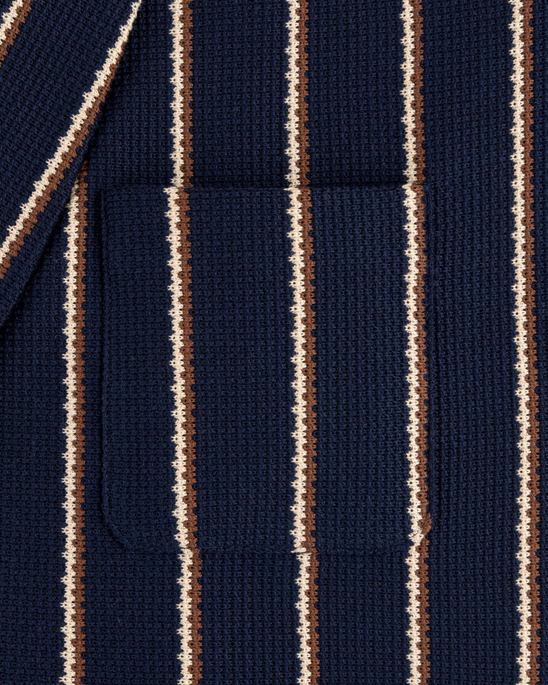Close-up of the Striped Jacquard Shawl Collar Jacket in navy with vertical white and brown stripes and a patch pocket.