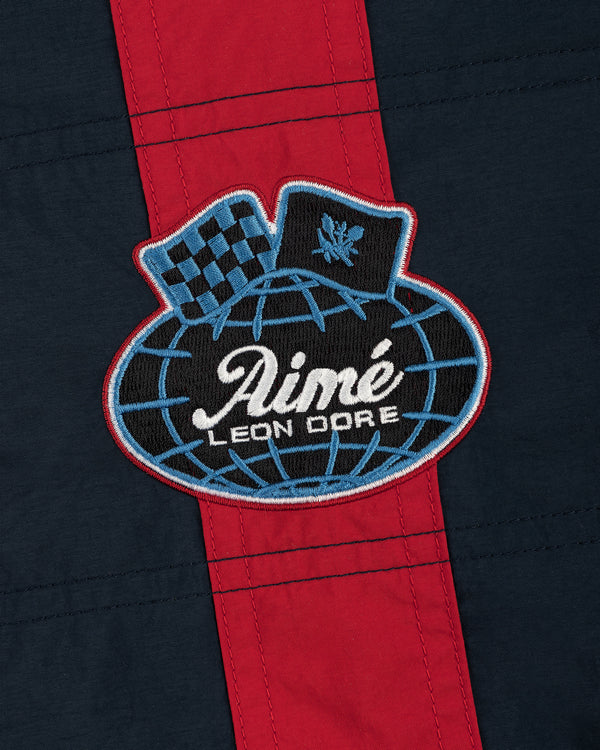 A patch on the Nylon Moto Jacket features Aimé Leon Dore on a globe, a checkered flag, and laurel on navy with red stripe.