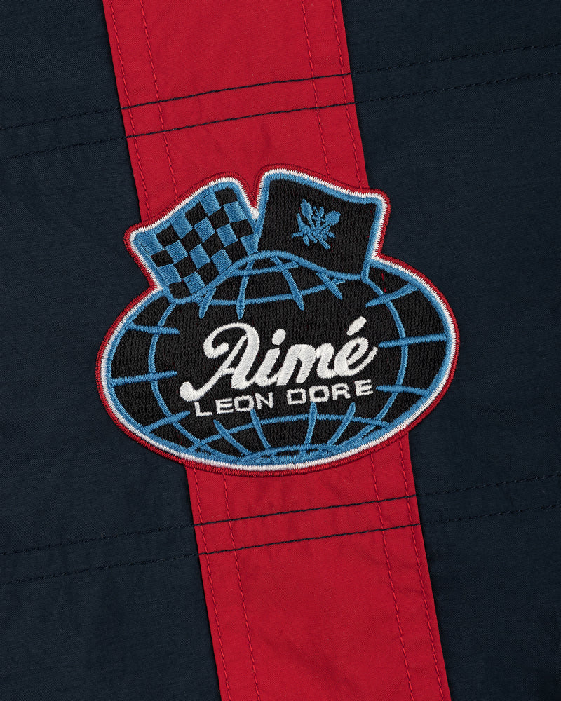 A patch on the Nylon Moto Jacket features Aimé Leon Dore on a globe, a checkered flag, and laurel on navy with red stripe.
