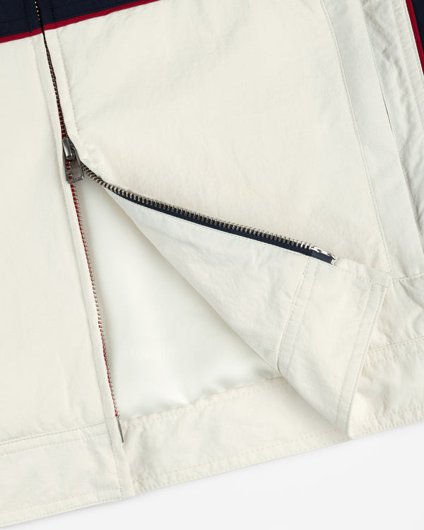 Close-up of an open zipper on the Nylon Moto Jacket, highlighting its cream and navy fabric, lining, and stitching.