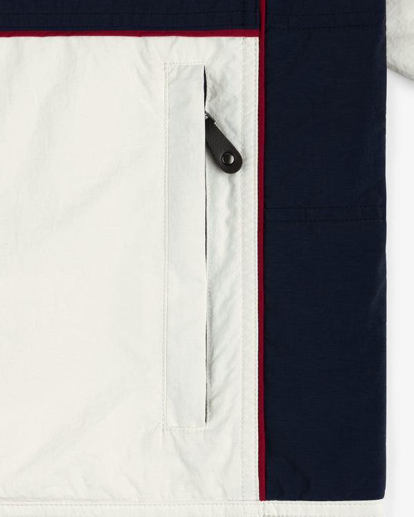 Close-up of Nylon Moto Jacket pocket with black zipper and navy blue and red trim on the side.
