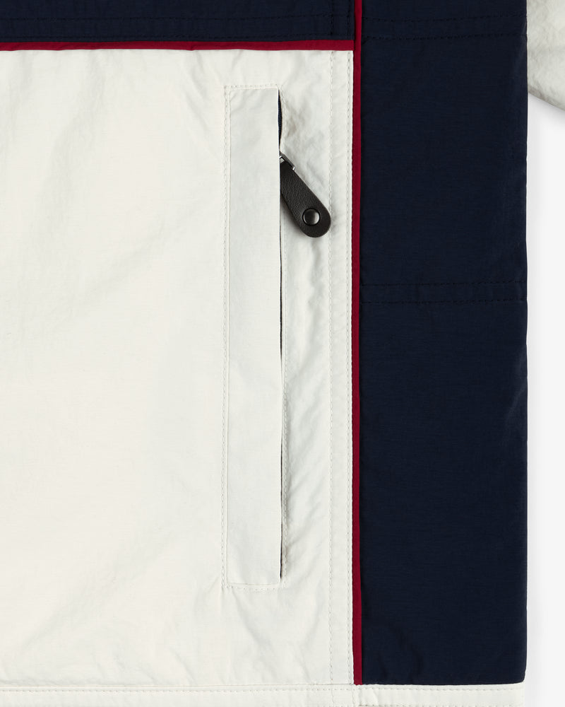 Close-up of Nylon Moto Jacket pocket with black zipper and navy blue and red trim on the side.