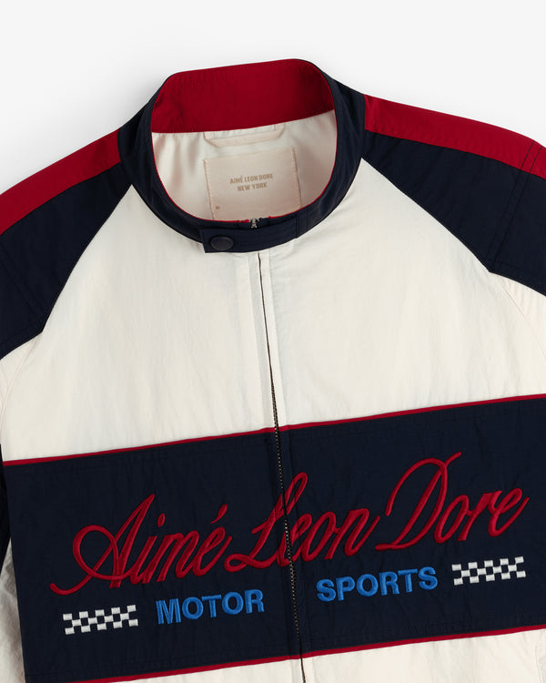 A cream, navy, and red Nylon Moto Jacket by Aimé Leon Dore with Motor Sports embroidered on the front.