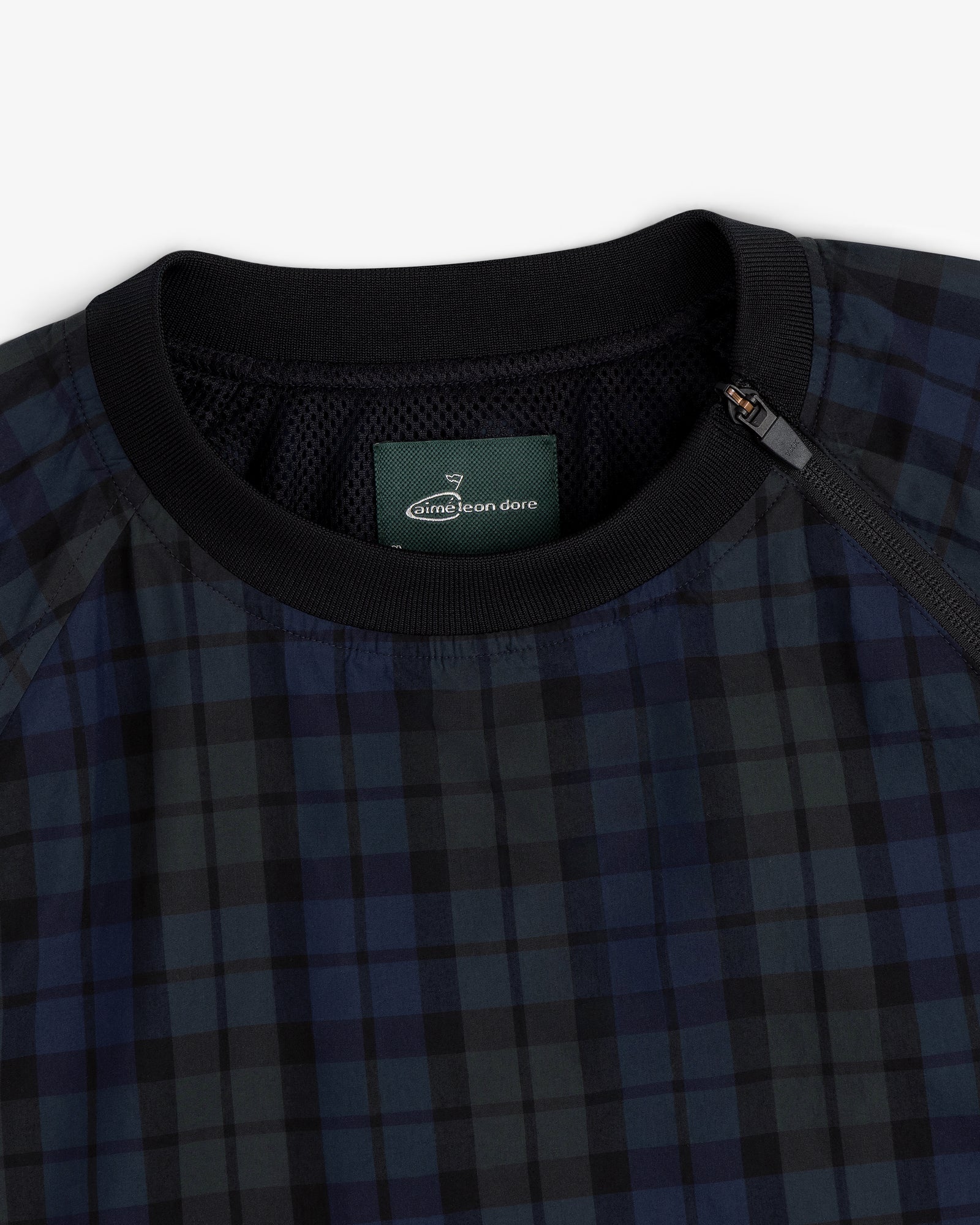 Close-up of the ALD Golf Blackwatch Pullover, featuring navy and black plaid with a black collar and Aimé Leon Dore label.
