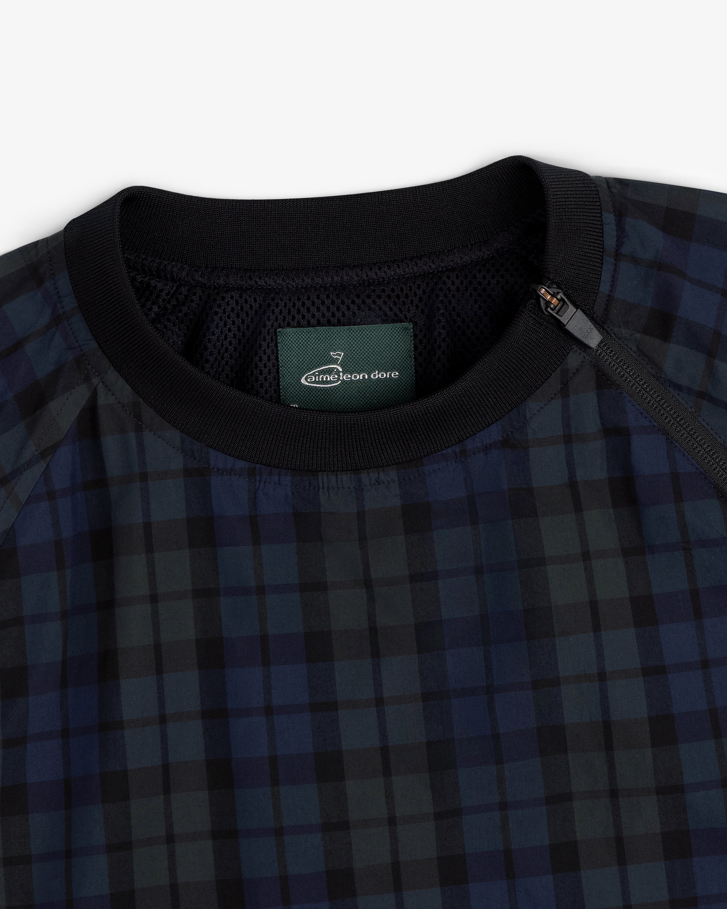 Close-up of the ALD Golf Blackwatch Pullover, featuring navy and black plaid with a black collar and Aimé Leon Dore label.
