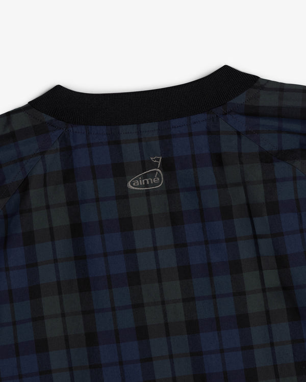 Close-up of the ALD Golf Blackwatch Pullover, a dark blue and black plaid shirt with a black collar and small logo.