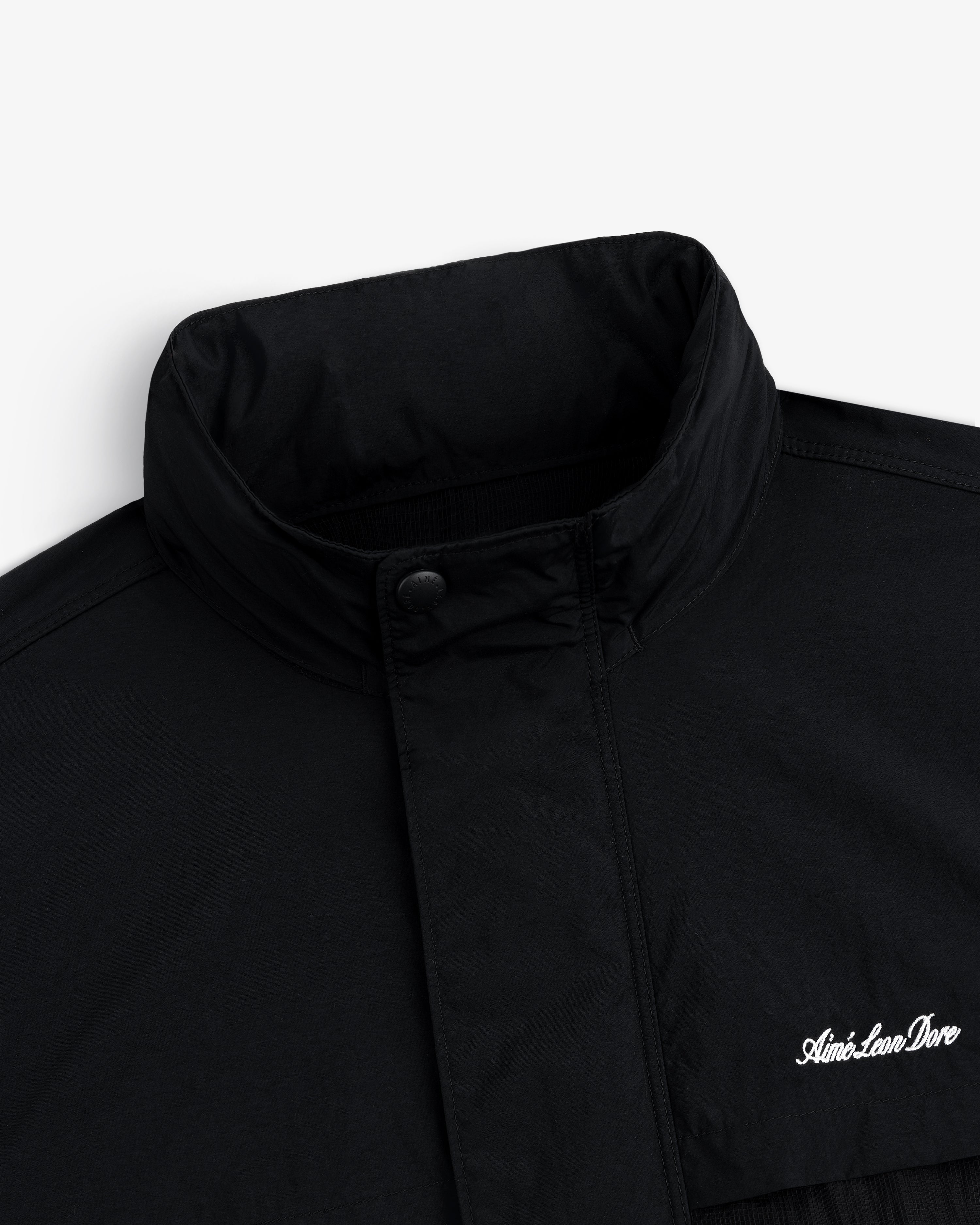 Close-up of a black Nylon Track Jacket with a high collar and "Aint-Lion-Dive" embroidered in white on the chest.