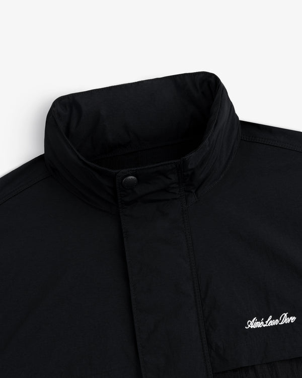 Close-up of a black Nylon Track Jacket with a high collar and "Aint-Lion-Dive" embroidered in white on the chest.