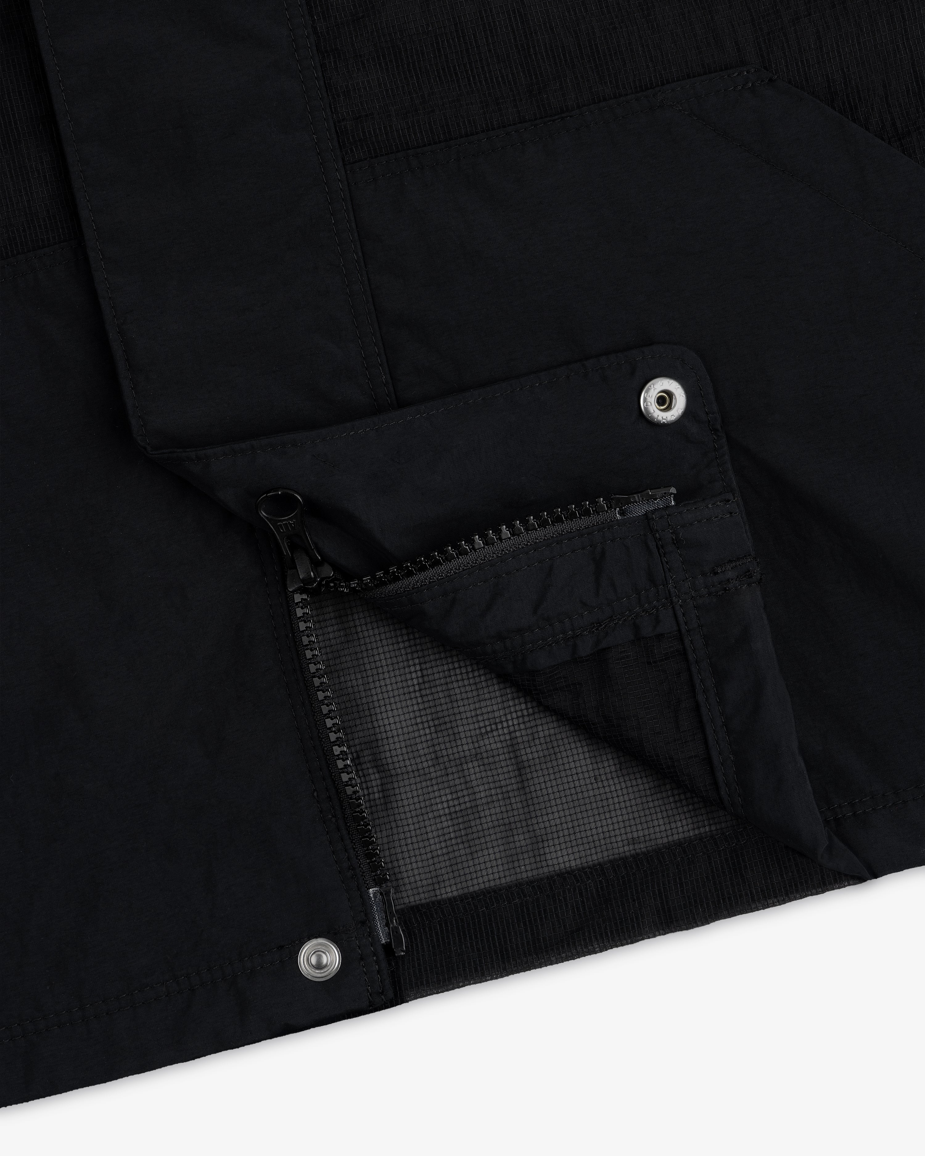 Close-up of the Nylon Track Jacket featuring a zippered pocket and metal snap buttons on black fabric.