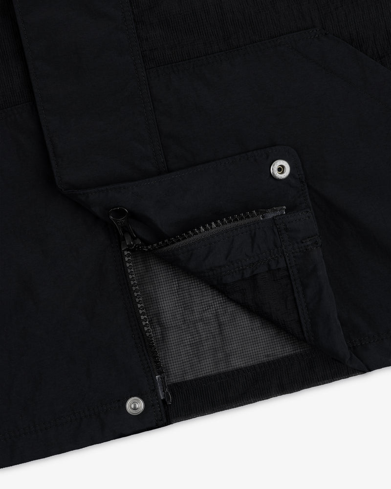 Close-up of the Nylon Track Jacket featuring a zippered pocket and metal snap buttons on black fabric.