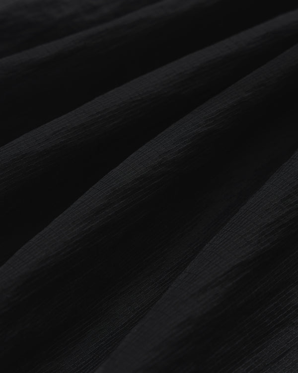 Close-up of black Nylon Track Jacket fabric with a textured, slightly ridged surface and soft, diagonal folds.
