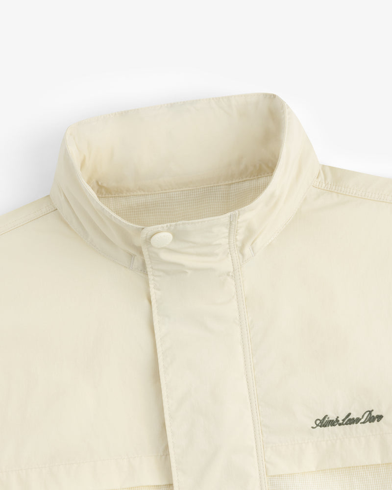 Close-up of the Nylon Track Jacket in cream, featuring a high collar and the Aimé Leon Dore logo embroidered on the chest.