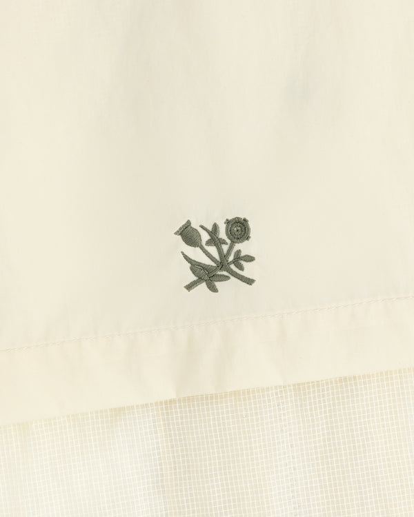 Green floral embroidery on cream nylon track jacket featuring a subtle checked pattern below.