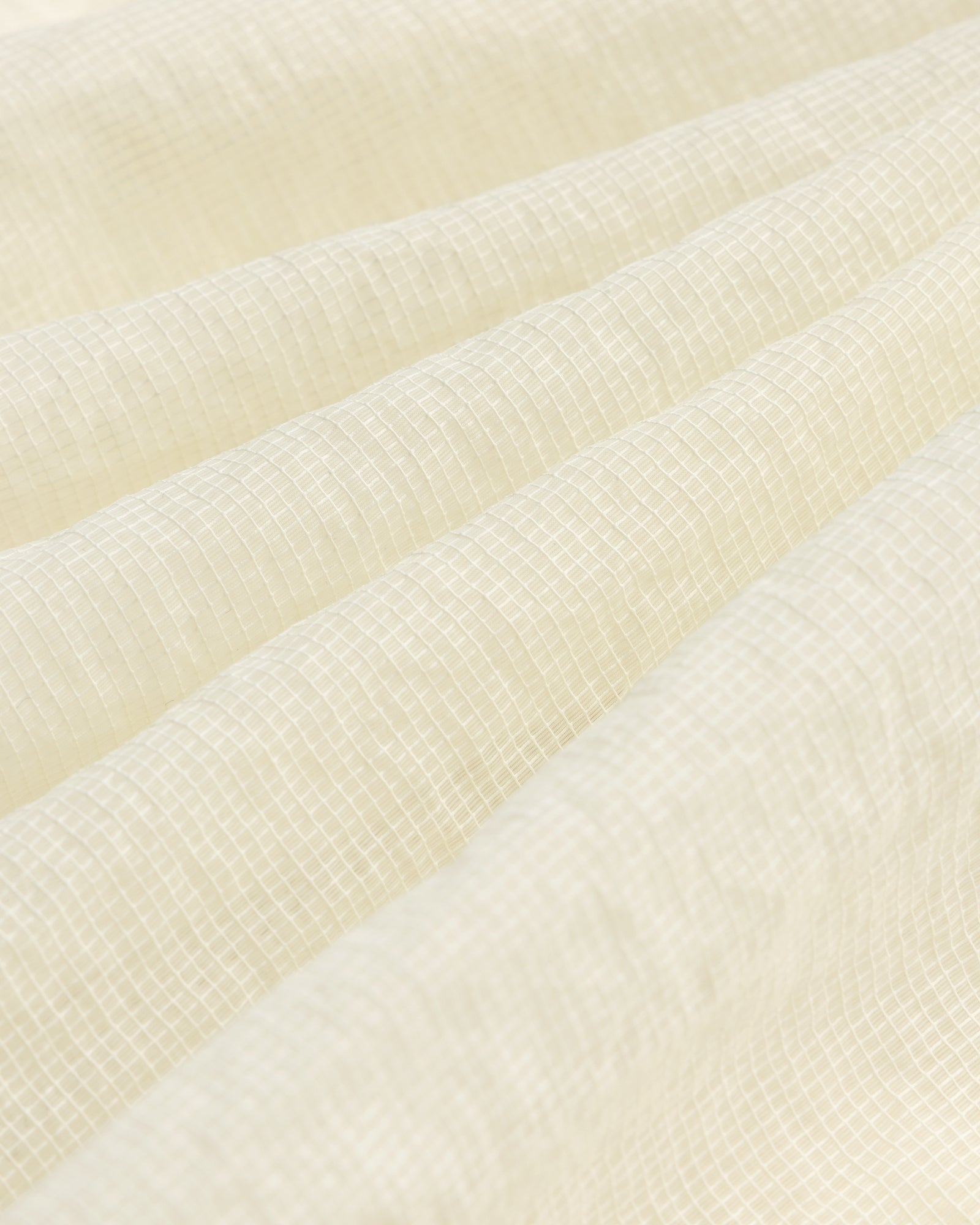 Close-up of the Nylon Track Jacket's white, textured fabric featuring a subtle grid pattern and gentle folds.