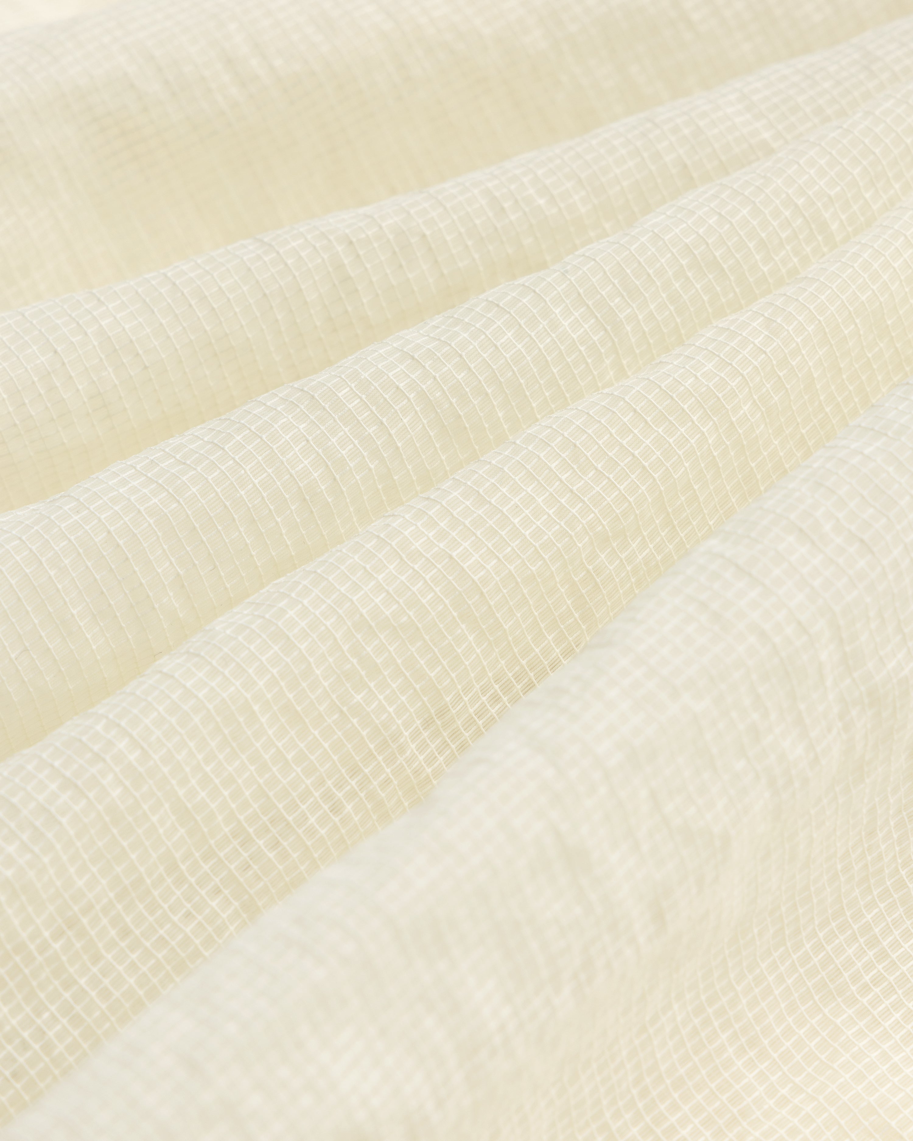 Close-up of the Nylon Track Jacket's white, textured fabric featuring a subtle grid pattern and gentle folds.