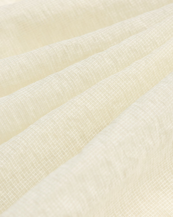 Close-up of the Nylon Track Jacket's white, textured fabric featuring a subtle grid pattern and gentle folds.