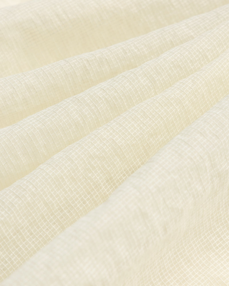 Close-up of the Nylon Track Jacket's white, textured fabric featuring a subtle grid pattern and gentle folds.