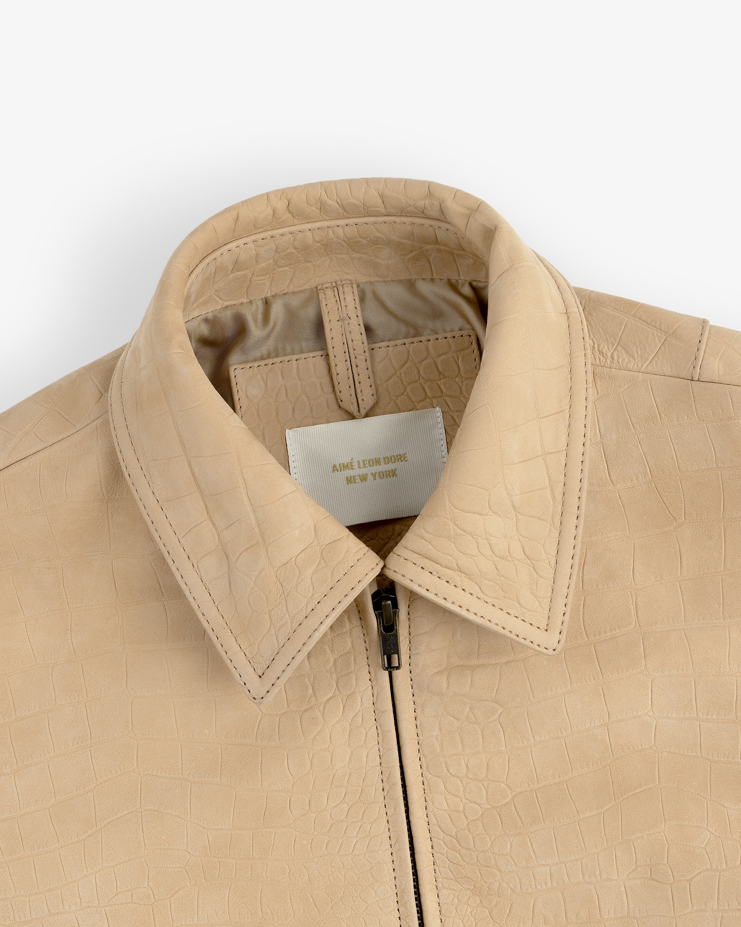 Close-up of a Croc-Embossed Nubuck Bomber Jacket with zipper and visible label inside the collar.
