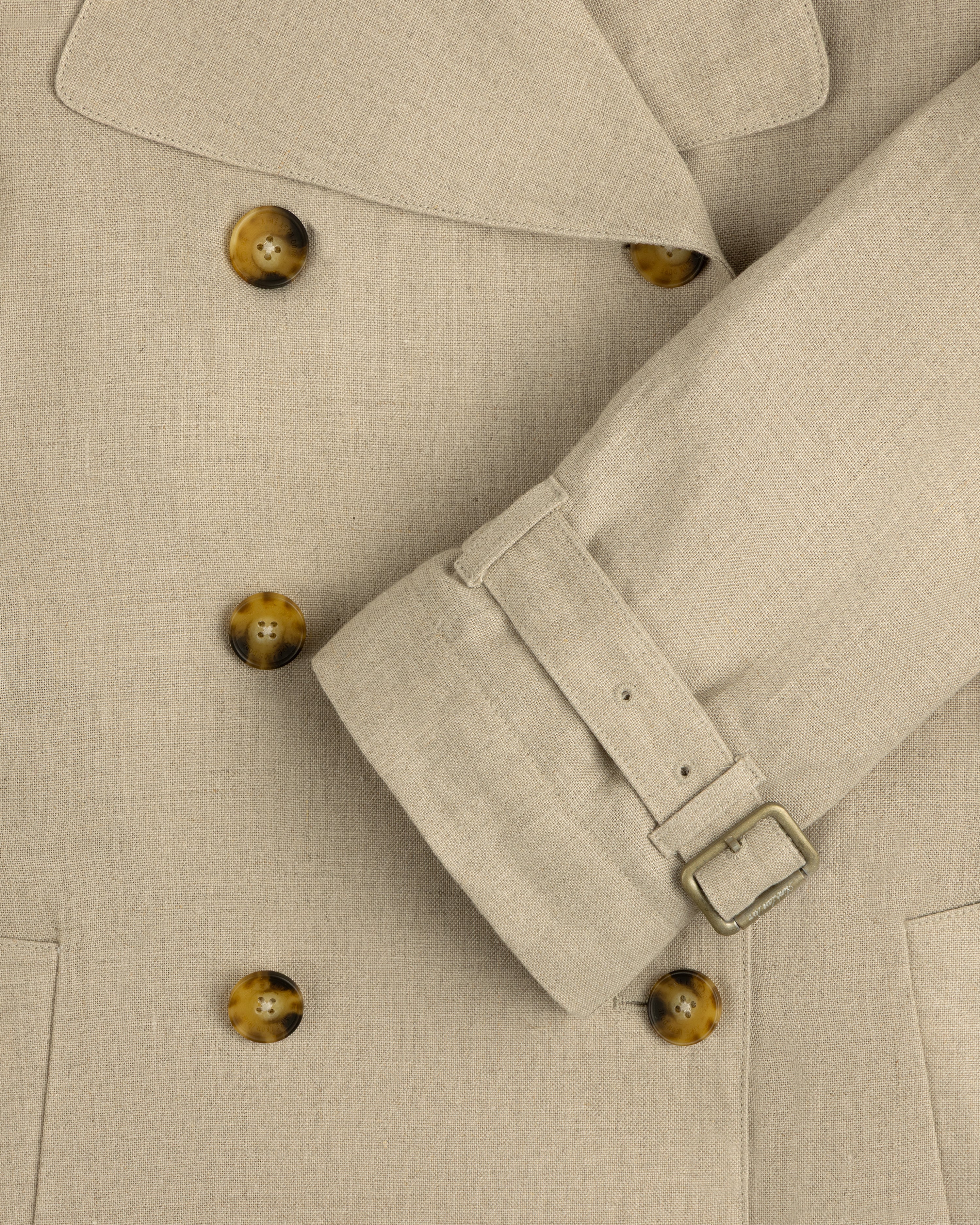 Close-up of Linen Trench Coat with brown buttons and belted cuff, highlighting the detailed fabric texture.