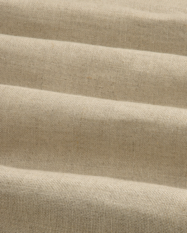 The Linen Trench Coat features beige, textured fabric with horizontal, wavy folds for a dynamic light and shadow effect.